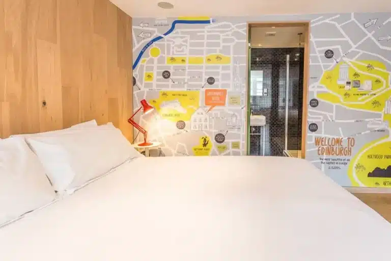 Double bed with wall of an illustrated map of Edinburgh city centre at The Grassmarket Hotel